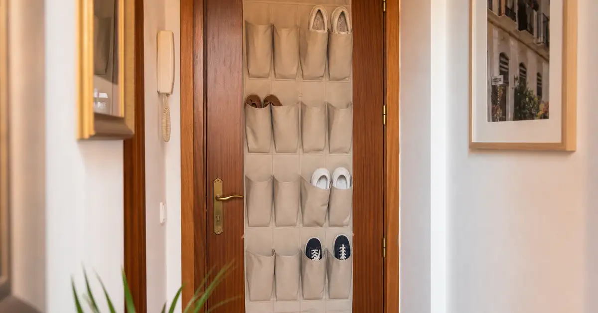 Organizador colgante de tela sobre la puerta con varios pares de zapatillas guardados, instalado sin taladrar